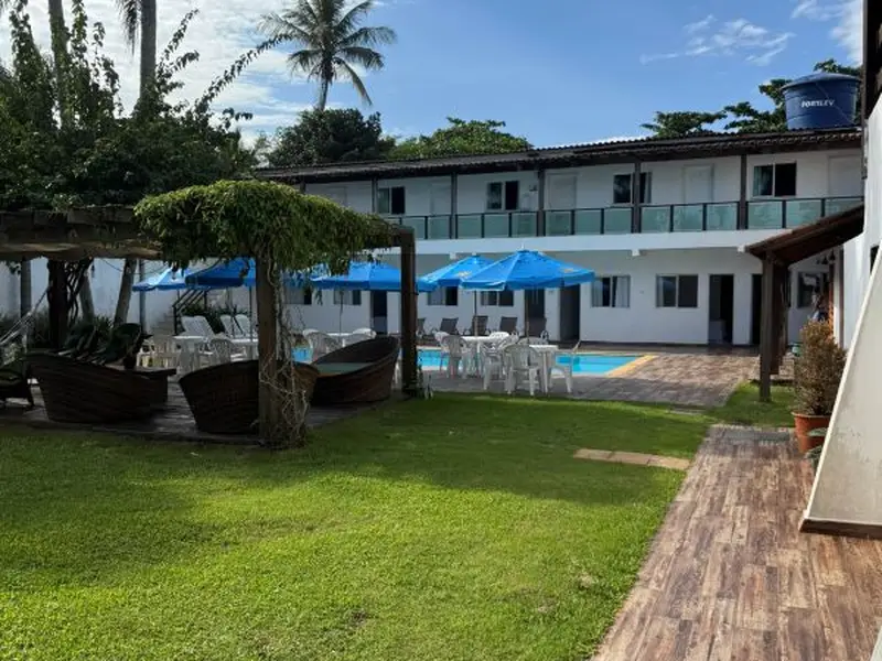Área de convivência com pergolado e jardim na Pousada Point Beach Acácias